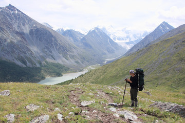 Fototapeta na wymiar Man with a backpack standing on the pass Kara-Turek, view of the Akkem Lake, Altai Mountains, Russia