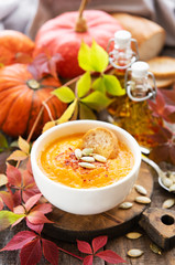 Bowl of pumpkin soup on rustic wooden background