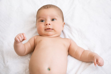 Close-up portrait of baby awake. Newborn baby lies on his back and tries to smile for the first time