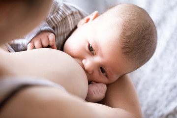 Close-up of mother breastfeeding and hugging newborn baby. Mom breast feeding her infant baby....