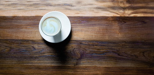 Top view,cup of hot coffee with foam and smoke on wooden table in the morning. copyspace for your text