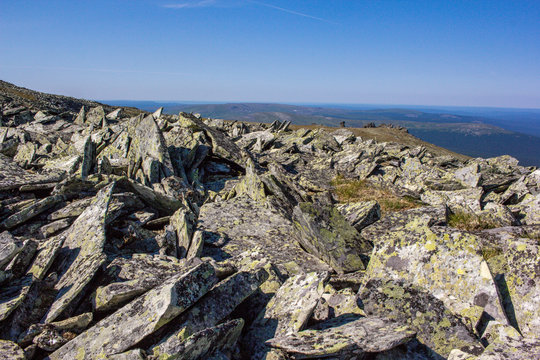 Huge boulders and kurumnik feature of the Ural Mountains. Texture of old stones with lichen on a background of blue sky. Stones of the Northern Ural.