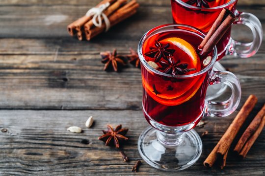 Mulled red wine with spices and orange in glass on a wooden rustic background. - Powered by Adobe