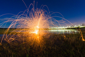Trajectory of burning sparks reflected on the river surface