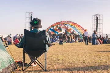 Foto op Plexiglas Back view of Man sitting chair on the grass, enjoying an outdoors music, culture, community event, festival,Funny group of young girls and boys at music festival, Happy teen at summer festival. © chartphoto