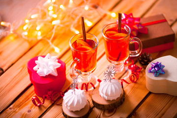 Mulled wine with spices and fruits on the wooden background. Beautiful Christmas decorations and gifts. Space for a text. Close up.