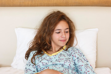 Naklejka premium Just awake pretty teenager girl with funny emotion face and wild hair on the bed