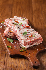 Raw pork ribs, on a plate sprinkled with spices.