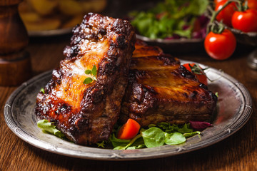 Roasted ribs, served on an old plate. Dark or balck background.