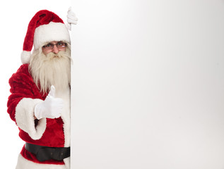 santa claus holds white empty board and makes ok sign