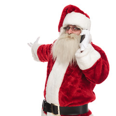 santa claus talking on the phone makes and inviting gesture