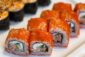 Orange sushi rolls California with caviar in a row close-up