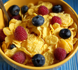 Cornflakes and different Berries - Blueberries and fresh Raspberries, blue wooden background.