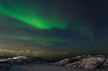 Fototapeta na wymiar Beautiful northern lights, aurora in the night sky over the snow-covered hills.