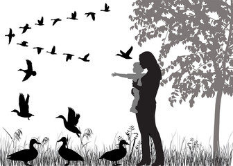 Woman with child in her arms looking at the flying ducks, in silhouettes