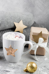 cozy winter weekend still life with cute ceramic cup , gift box and knitted sweaters on a gray shabby background