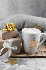 cozy winter weekend still life with cute ceramic cup , gift box and knitted sweaters on a gray shabby background