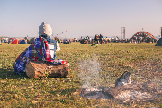 Back View Of Man Sitting Wooden On The Grass, Enjoying An Outdoors Music, Culture, Community Event, Festival,Funny Group Of Young Girls And Boys At Music Festival, Happy Teen At Winter Festival.