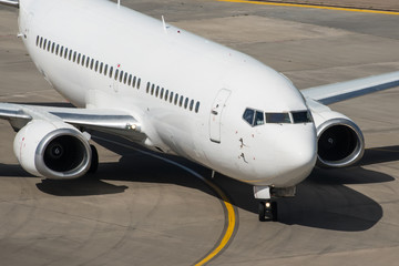 White modern passenger civil airplane taxiing at international airport