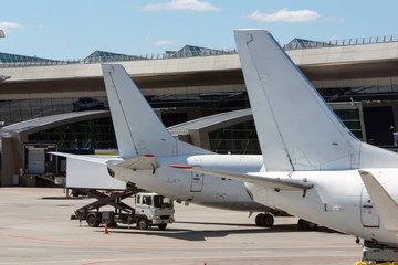 Fototapeta na wymiar White modern twin engine civil airplane standing on parking place at ground maintenance at International airport.