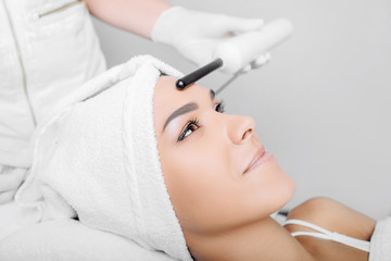 woman getting electric darsonval facial massage procedure at beauty salon.