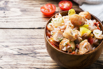Stewed rice with chicken and vegetables in a wooden bowl.