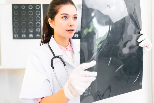 healthcare, medical and radiology concept - two asian doctors looking and discussion of x-ray film image