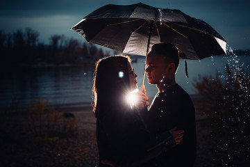 young man and woman under an umbrella and rain
