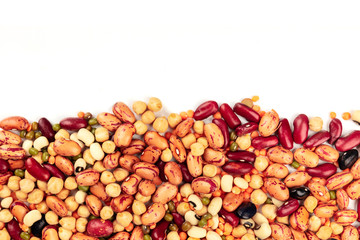 Various types of legumes, shot from the top on a white background with a place for text. Red kidney and pinto beans, lentils, chickpeas, soybeans. An abstract pulses texture with copy space