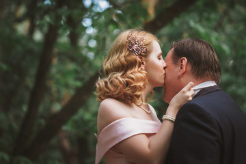 Fototapeta premium bride and groom kissing in the summer forest
