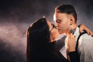 Couple in fashionable clothes on a dark smoky background