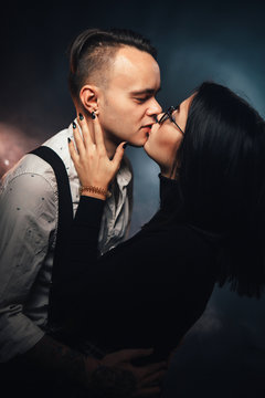 Couple in fashionable clothes on a dark background with smoke