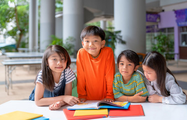 Fototapeta premium Cute little Asian children reading books together while sitting on steps outdoors