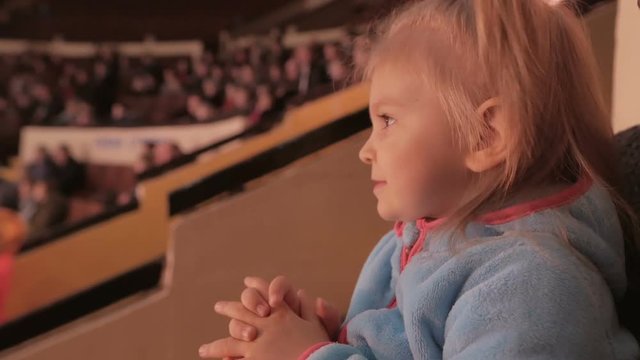 Little girl attentively watches and laughs during a circus performance.