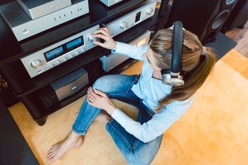 Woman with headphones listening to music via the Hi-Fi stereo in her home - obrazy, fototapety, plakaty