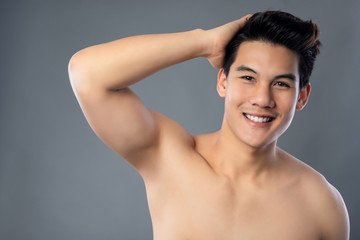 Portrait of smiling shirtless young handsome Asian man with hand in hair