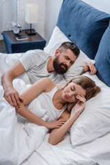 Fototapeta na wymiar bearded young man and beautiful girl sleeping in big white bed in morning