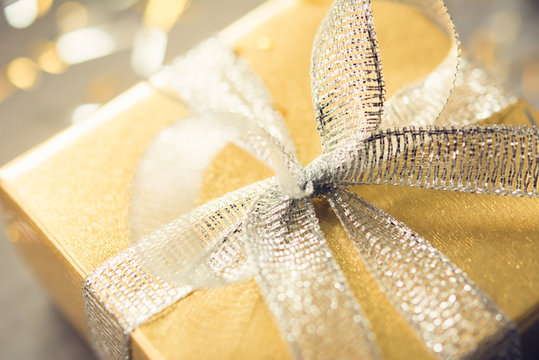 Gift Box With Shiny Glittering Silver Ribbon Bow And Gold Wrapping Paper