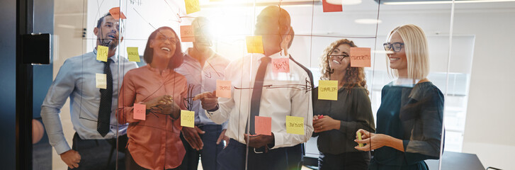 Diverse coworkers brainstorming together with sticky notes in an - obrazy, fototapety, plakaty