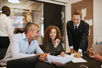 Smiling coworkers going over paperwork together in an office mee