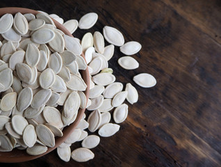 Dried pumpkin seeds on old dark weathered wood with copy space