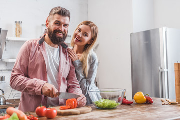 Smiling couple preparing dinner in kitchen