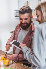 Wife holding digital tablet and husband looking at blank screen