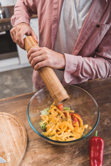 cropped view of man salting salad in glass bowl
