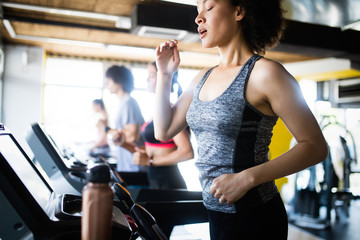 Fototapeta na wymiar Young woman running on a treadmill in health club.