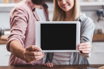 cropped view of couple holding digital tablet with blank screen