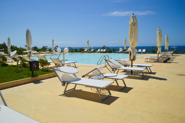 view of the pool in the hotel grounds with white sun loungers around