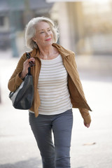 Fototapeta premium Attractive senior woman walking through town