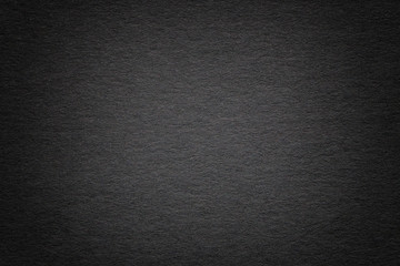 Texture of old dark black paper background, closeup. Structure of dense cardboard.