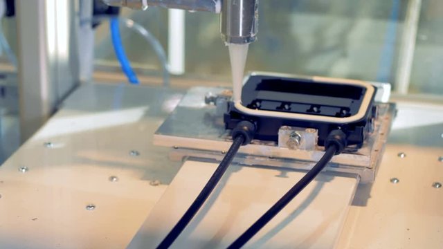 Factory machine squeezes glue on a panel, close up. 